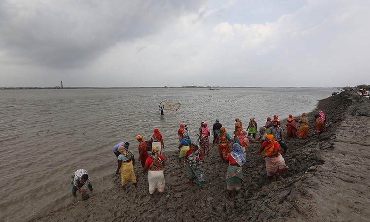 জোয়ারের পানি ঢোকার আশঙ্কায় মাটি দিয়ে বেড়িবাঁধ মজবুত করছেন এলাকাবাসী।