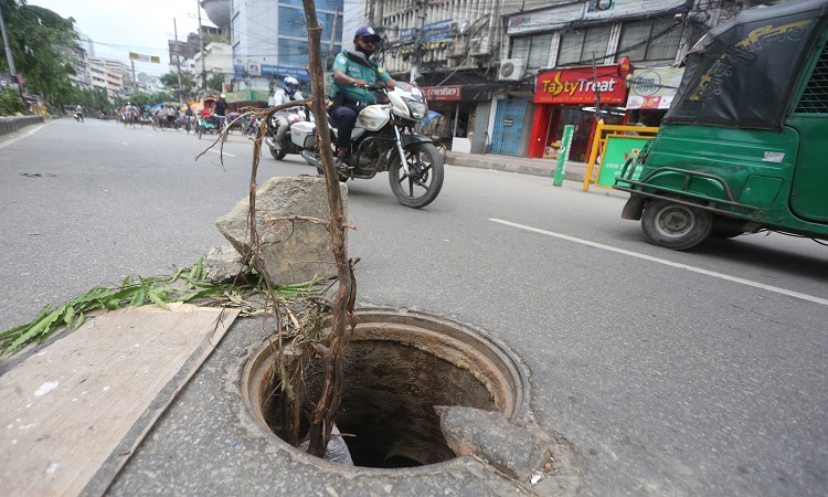 রাজধানীর দৈনিক বাংলা মোড়ে সড়কের ওপর খোলা ম্যানহোল। সেখানে দেয়া হয়েছে গাছের ডাল। এসব ঢাকনাবিহীন ম্যানহোল যা স্থানীয়দের ভাষায় 'মৃত্যু ফাঁদ' যেকোনো সময় বড় দুর্ঘটনা ঘটাতে পারে। ছবিটি সোমবারের।